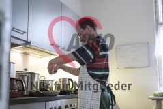Ein Mann steht in einer Küche und bereitet Spiegeleier vor