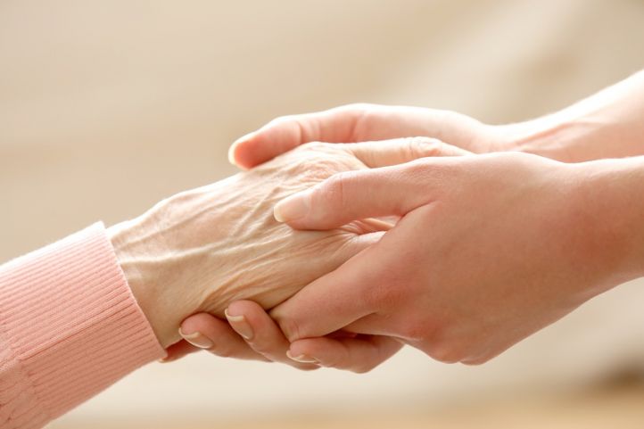 Eine ältere Frauenhand liegt in den Händen von zwei jungen Frauenhänden