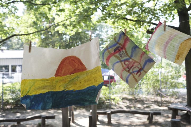 Eine Kinderzeichnung an einer Wäscheleine am Baum aufgehängt zeigt eine Sonne und den Schriftzug Für Dich