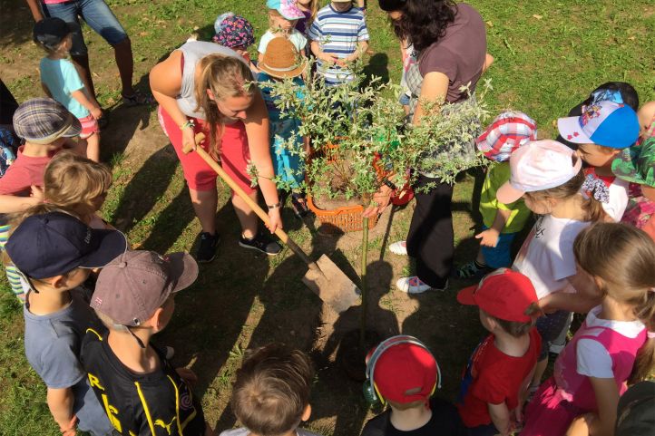 In einer Kita in Sachsen wird ein Schlüsselbäumchen gepflanzt zum Kindetag mit Erzieherin und Kindern