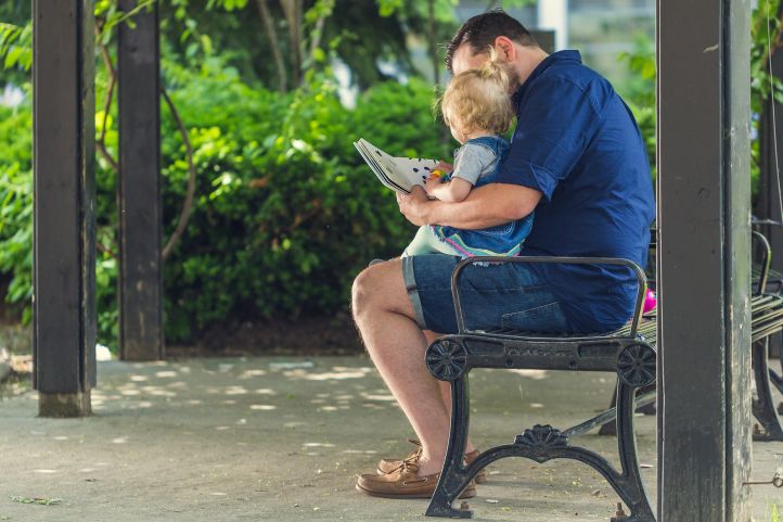 Ein Vater liest seinem Bild ein Kinderbuch vor