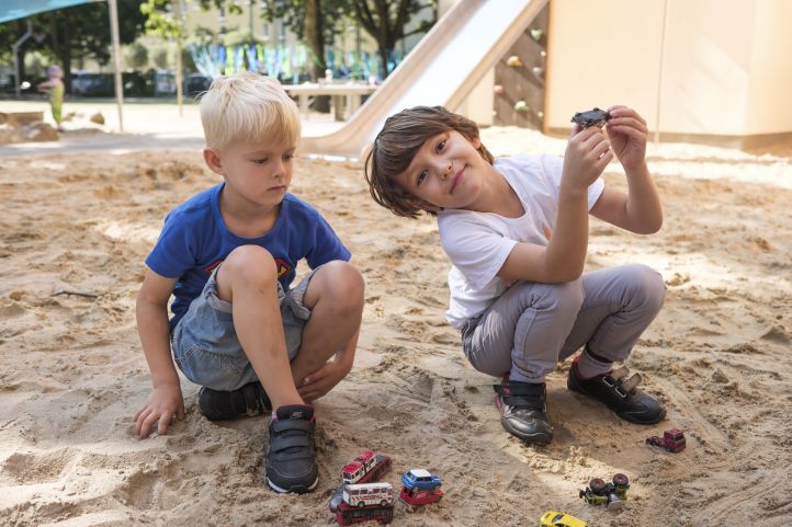 zwei Kinder spielen im Sandkasten
