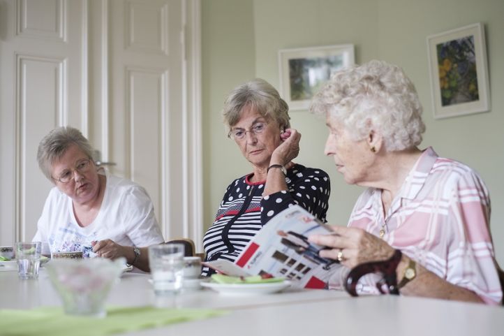 Drei ältere Frauen in der Kafferunde, die rechte zeigt eine Zeitschrift