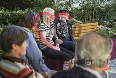 Mehrere alte Menschen Seniorinnen sitzen auf einer Parkbank und unterhalten sich