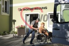 Ein Mann fährt eine alte Frau Seniorin im Rollstuhl in einen Transporter