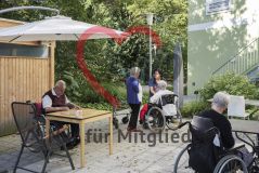 Mehrere Personen Seniorinnen und Senioren im Rollstuhl sind auf der Terrasse