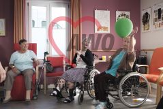 Mehere alte Frauen Seniorinnen und Senioren im Rollstuhl spielen mit einem Luftballon