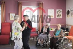 Zwei alte Menschen Seniorinnen und Senior tanzen und zwei Personen im Rollstuhl schauen zu