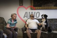 Eine alte Frau Seniorin und ein alter Mann Senior sitzen mit einem Hund in einem Aufenthaltsraum