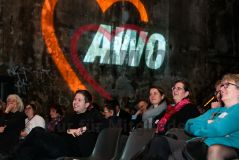 AWO Neujahrsempfang 2023: Das vor dem AWO Logo sitzende Publikum lacht, darunter AWO Vorstandsvorsitzende Brigitte Döcker und SPD Generalsekretär Kevin Kühnert