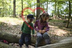 Junge und Mädchen im Wald, auf einem Baumstamm sitzend